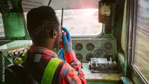 African train driver talking radio communication or walkie talkie in  interior room to control place of train photo