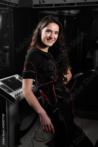 Girl in EMS suit in gym. Sport training in electrical muscle stimulation suit. photo