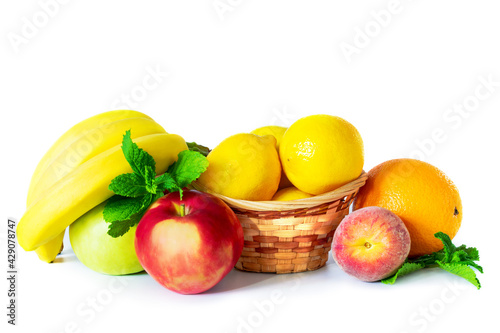 Photo of a still-life from fruit with a small basket and mint leaves on a white background