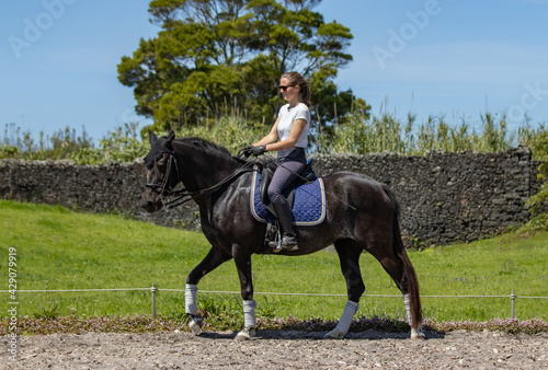 Happy woman riding black Lusitano horse, beautiful mare, outdoors.