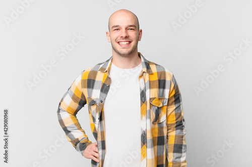 Foto bald man smiling happily with a hand on hip and confident, positive, proud and f