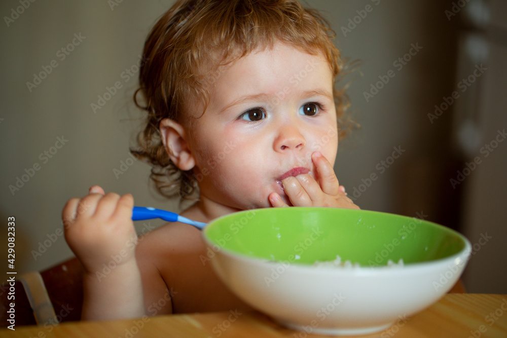 Happy baby eating himself with a spoon. Lick tasty fingers. Happy baby eating himself with a spoon. Lick tasty fingers.
