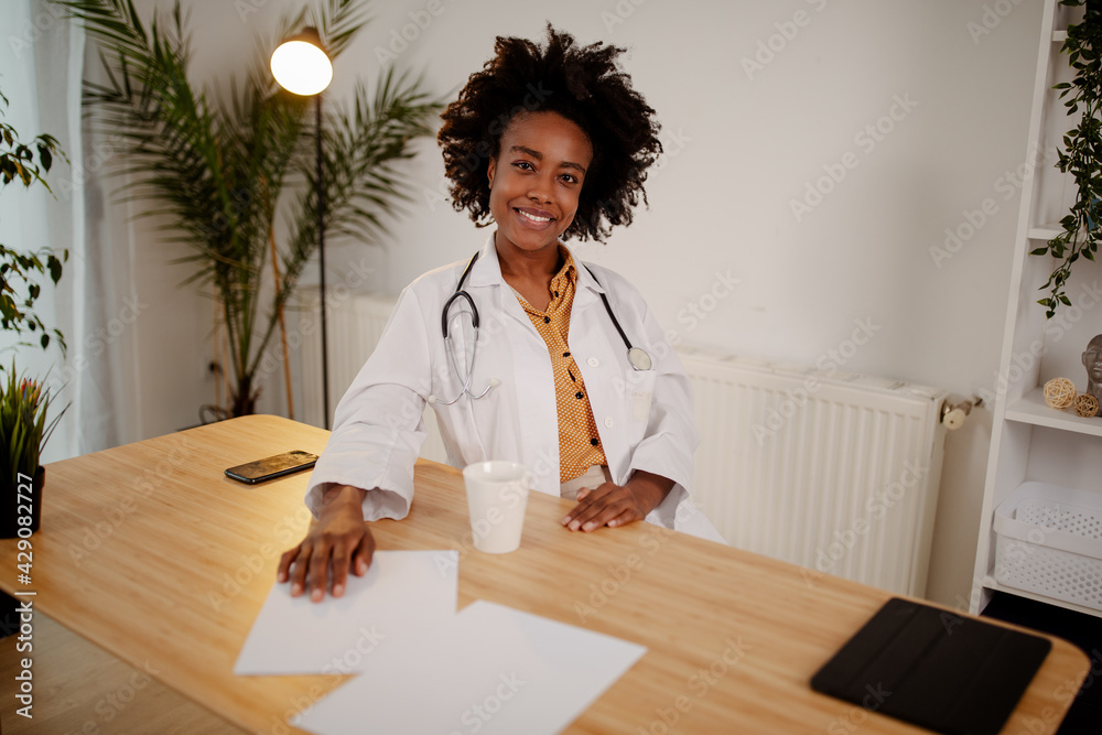 Female doctor sitting at office desk and smiling at camera, health care and prevention concept. Female doctor sitting at office desk and smiling at camera, health care and prevention concept.