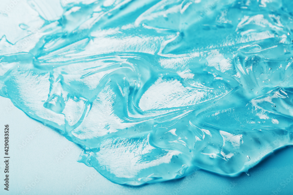 Gel with hyaluronic acid in the form of a smear of glossy texture on a cyan background. Gel with hyaluronic acid in the form of a smear of glossy texture on a cyan background.