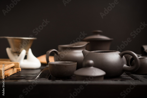 Asian set of utensils for the tea party on a dark background. The ceremony, process, teapot, cup, clay, tradition