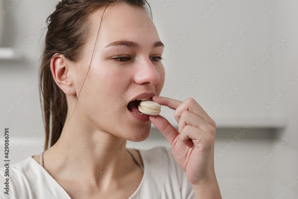 Beautiful Caucasian woman holds in hand and eats macaroons Beautiful Caucasian woman holds in hand and eats macaroons