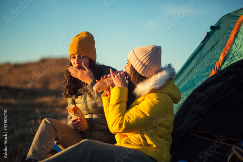 Hikers eating food near tent at mountain