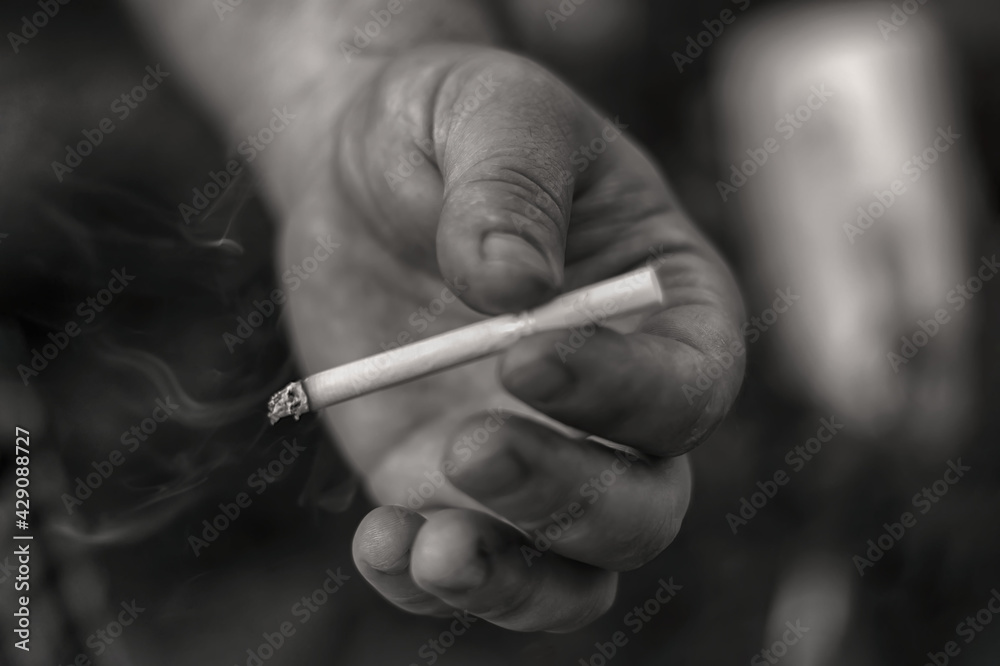 Background Hand of a man, a smoker, holding a cigarette black and white, monochrome photo. The 
