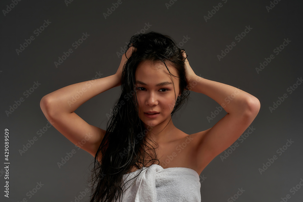 Young beautiful asian half naked woman in bath towel tousled her hair with one hand