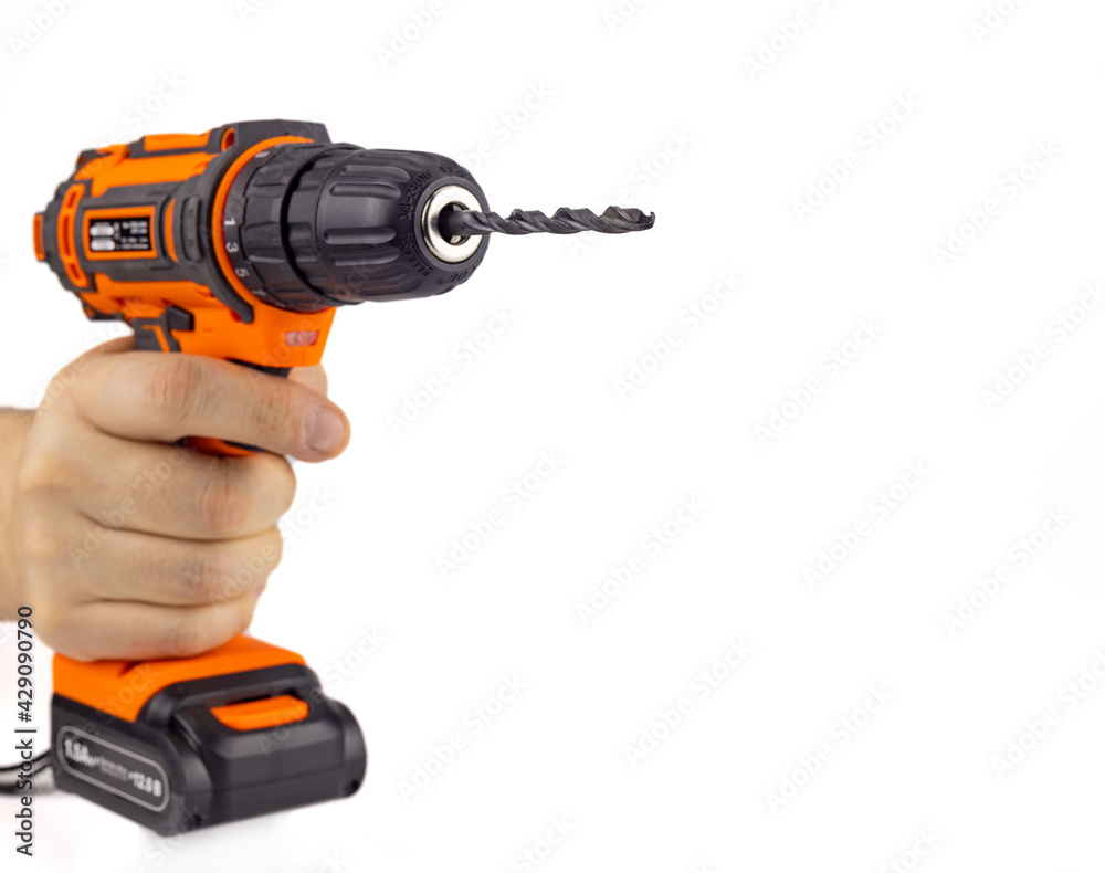 Electric drill with a drill bit in hand. A screwdriver on the battery. Isolated on a white background, close-up, selective focus.