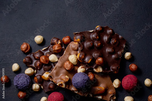 Chocolate bar, crushed pieces of dark chocolate and nuts. Praline Chocolate sweets. Copy space