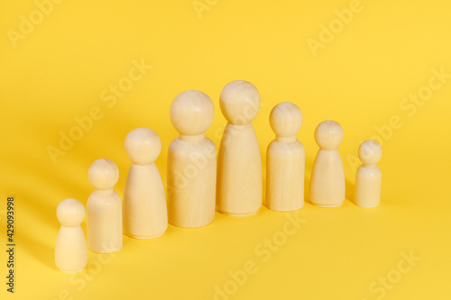 Family of eight 8 members made from wooden figurines on yellow background. Family with many children, multi-child or multi-member family. Demographic policy. © photo-lime