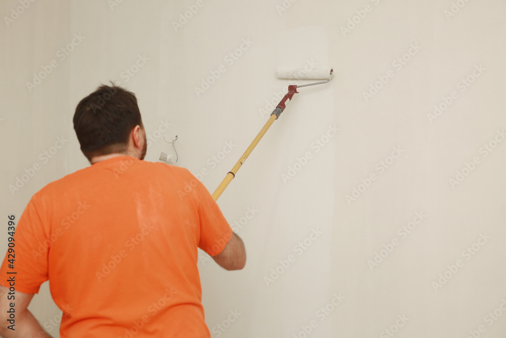Male painting wall with paint roller. Painting apartment, renovating with white color paint. Room renovations at house. Male painting wall with paint roller. Painting apartment, renovating with white color paint. Room renovations at house.