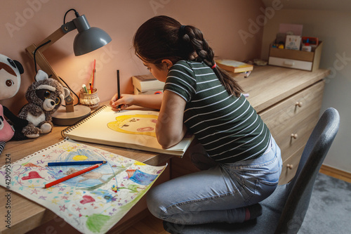 School girl practising and learning to draw.She sitting at the table in her room.	
