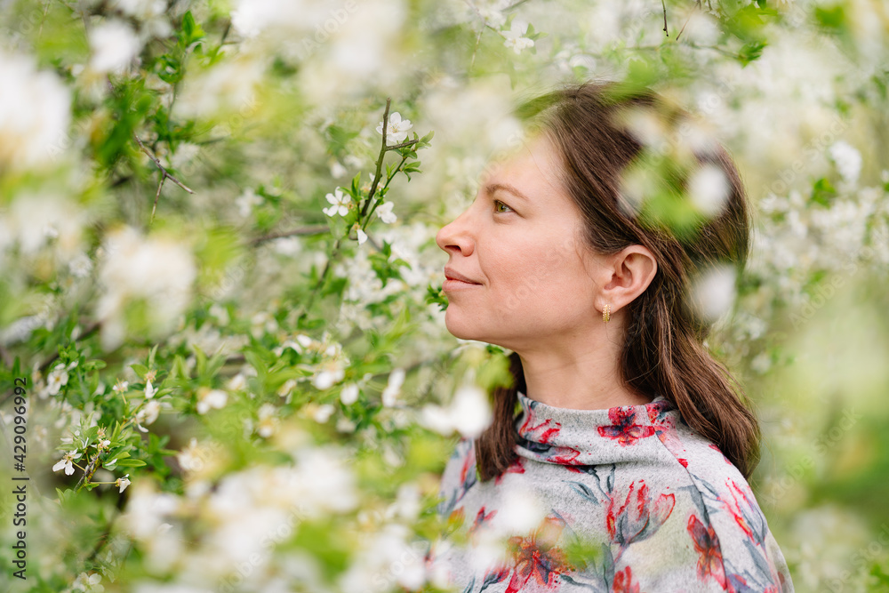 portrait of a beautiful young woman by blooming tree in spring portrait of a beautiful young woman by blooming tree in spring