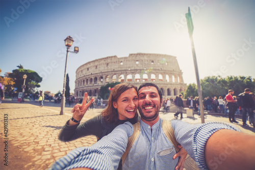 Canvas Print Happy caucasian couple is taking a selfie smiling at the camera in front of the colosseum in Rome