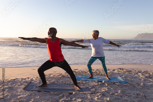 Senior african american couple performing stretching exercise together at the beach