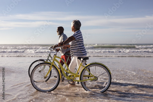 Happy senior african american couple with bicycles walking together on the beach © wavebreak3