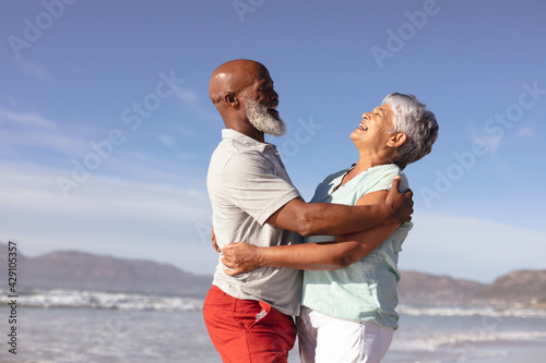 Happy senior african american couple hugging each other on the beach