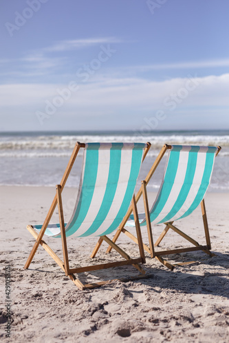 View of two deck chairs on the beach with sea waves