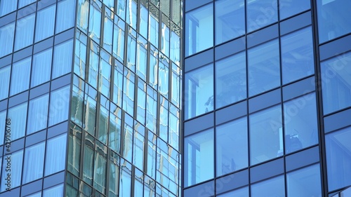 The glazed facade of an office building with reflected sky. Modern architecture buildings exterior background. Clouds sky reflection.
