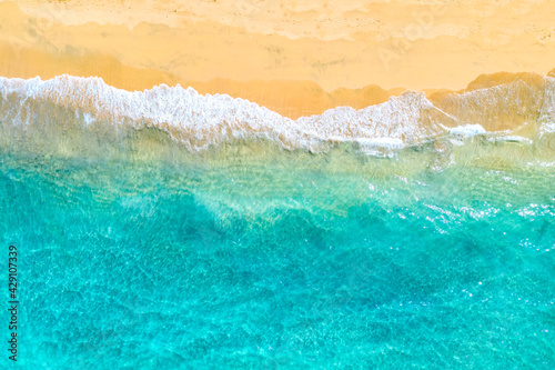 Vacation travel background. Top view aerial drone photo of ocean seashore with beautiful turquoise water and foam sea waves. Caribbean resort.