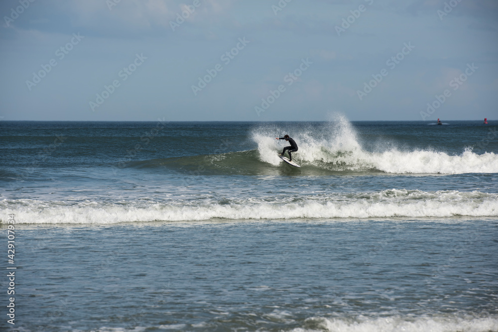 A lone male surfer wearing a black wet suit cutting back on wave as he surfs Florida's east coast near Daytona Beach, USA. A lone male surfer wearing a black wet suit cutting back on wave as he surfs Florida's east coast near Daytona Beach, USA.