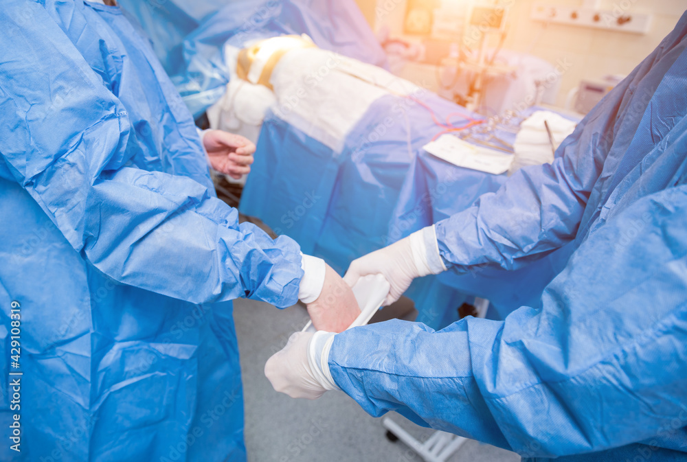 Assistant helps the surgeon put on latex gloves and surgical gown before the operation. Assistant helps the surgeon put on latex gloves and surgical gown before the operation.