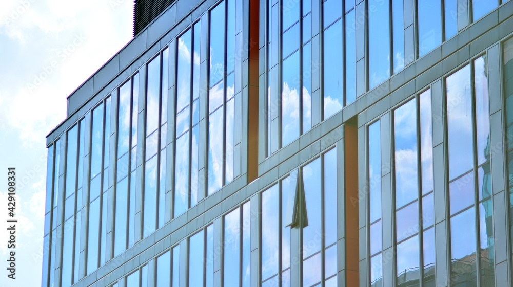 The glazed facade of an office building with reflected sky. Modern architecture buildings exterior background. Clouds sky reflection. The glazed facade of an office building with reflected sky. Modern architecture buildings exterior background. Clouds sky reflection.