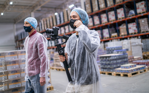 Young operators group in medical protective suit with camera on stabilizer records video