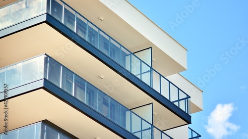 A fragment of modern architecture, walls and glass. Windows and balconies of a residential building against a blue sky. Detail of New luxury house and home complex. Part of city real estate property a