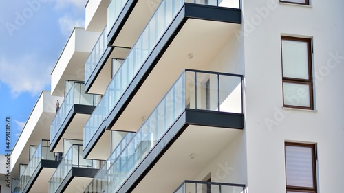 A fragment of modern architecture, walls and glass. Windows and balconies of a residential building against a blue sky. Detail of New luxury house and home complex. Part of city real estate property a