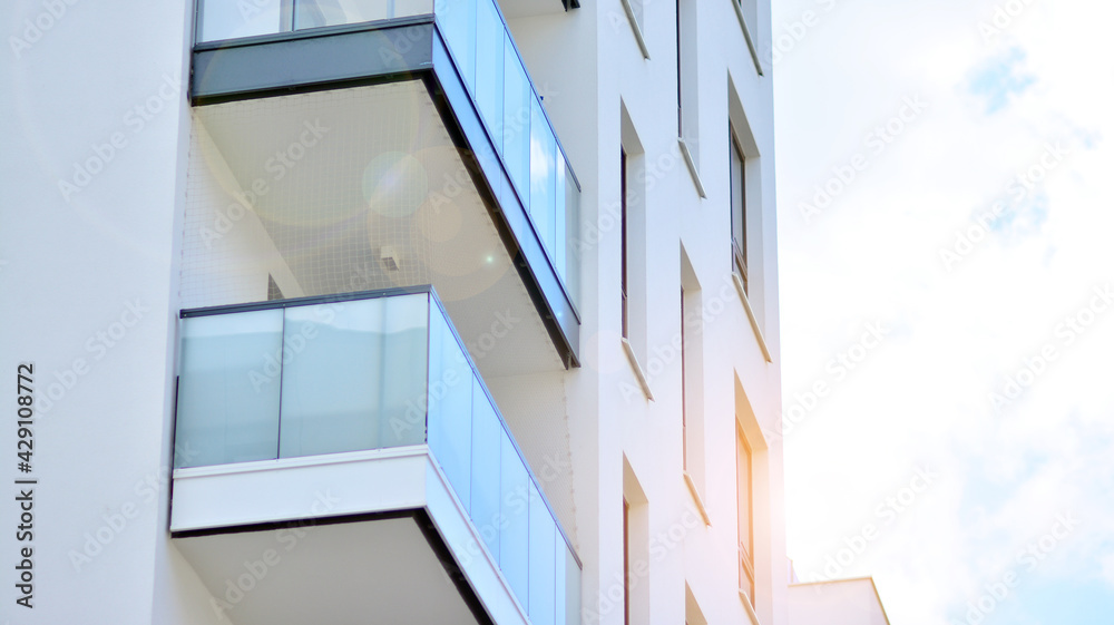 Obraz premium Detail of new luxury house and home complex. Glass surface with sunlight. Rising sun on the horizon. Part of modern residential apartment with flat building exterior. 