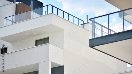 A fragment of modern architecture  walls and glass. Windows and balconies of a residential building against a blue sky. Detail of New luxury house and home complex. Part of city real estate property a