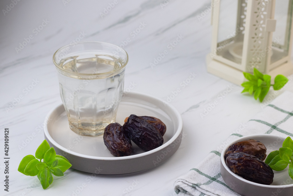 Kurma dan Air Putih, Medjool Dates and water on marble white background. Breakfasting concept in Ramadan month. Islamic template for text background. Kurma dan Air Putih, Medjool Dates and water on marble white background. Breakfasting concept in Ramadan month. Islamic template for text background.