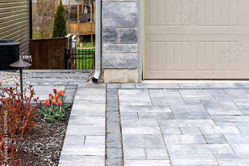 Luxury hardscape driveway shows pavers with pattern and  and gravel and slab steps along the sideyard. photo