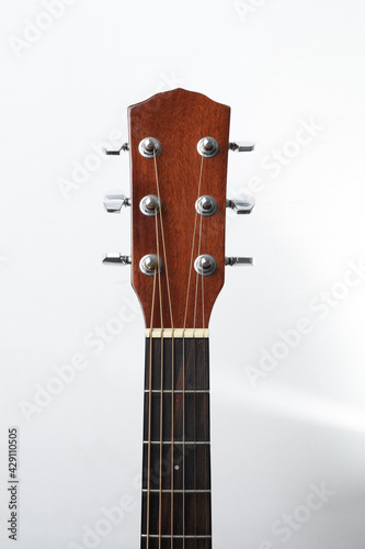 Acoustic guitar neck with tuning pegs on a white background © grthirteen