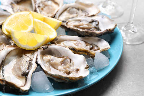 Cuadro en lienzo Fresh oysters with lemon on grey table, closeup