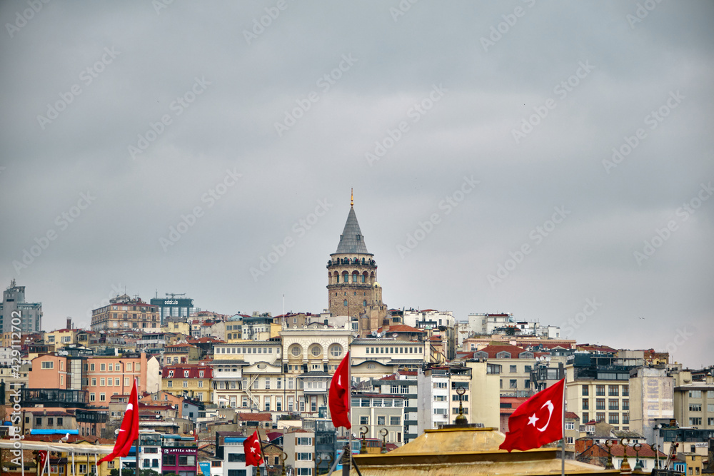 04.03.2021. istanbul turkey. Galata tower during rainy day and overcast weather. Many turkish flag and huge cloudy sky.