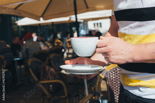 A man is drinking coffee in an outdoor restaurant.
