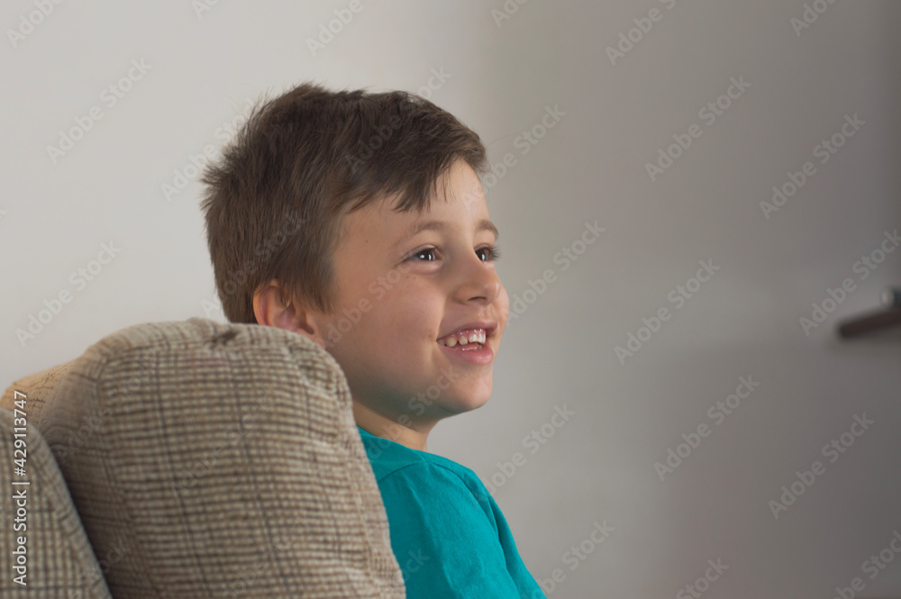 Young boy smiling using a blue t-shirt and looking to the side