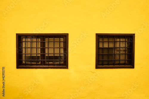 old two windows in the yellow wall