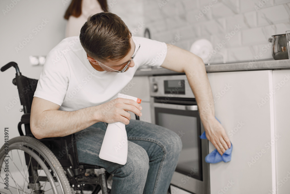 Young Handicapped Man On Wheelchair Cleaning Stove Young Handicapped Man On Wheelchair Cleaning Stove