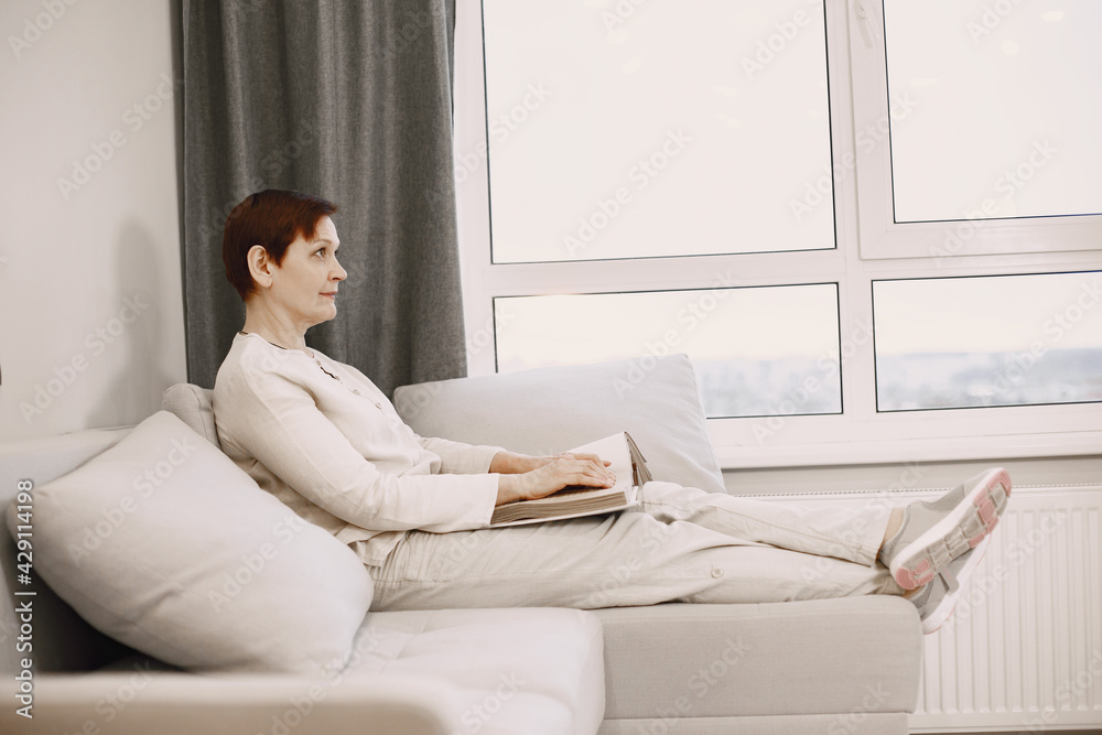 Mature woman read braille book on couch Mature woman read braille book on couch