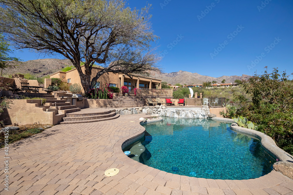 Swimming pool with hot tub and terraced patio at a luxury home in a desert environment.