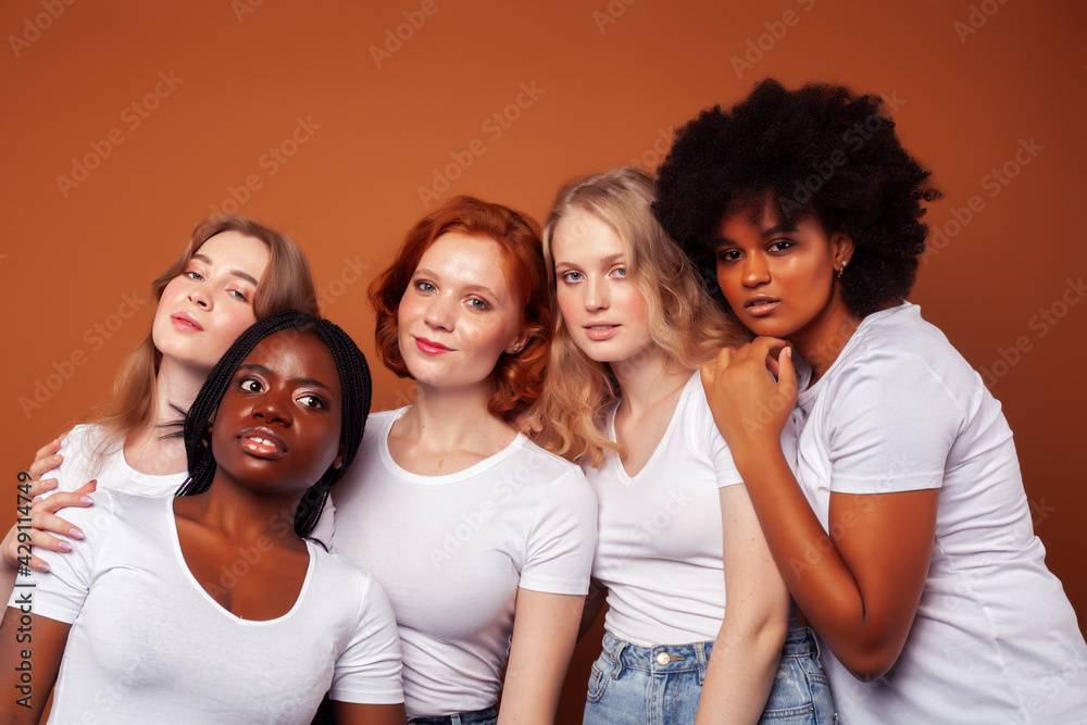 Obraz premium young pretty caucasian, afro, scandinavian woman posing cheerful together on brown background, lifestyle diverse nationality people concept
