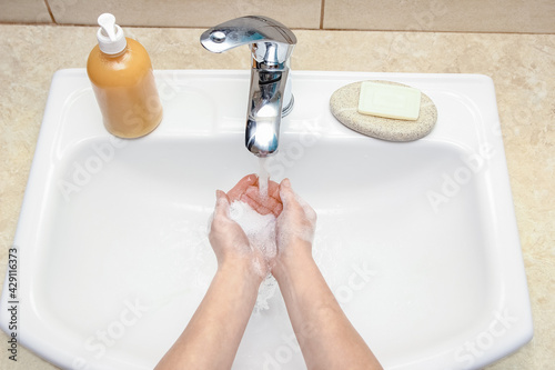 Fototapeta Naklejka Na Ścianę i Meble -  A Hands with soap are washed under the tap with water. Clean from infection and dirt and virus. At home or in the hospital ablution office.