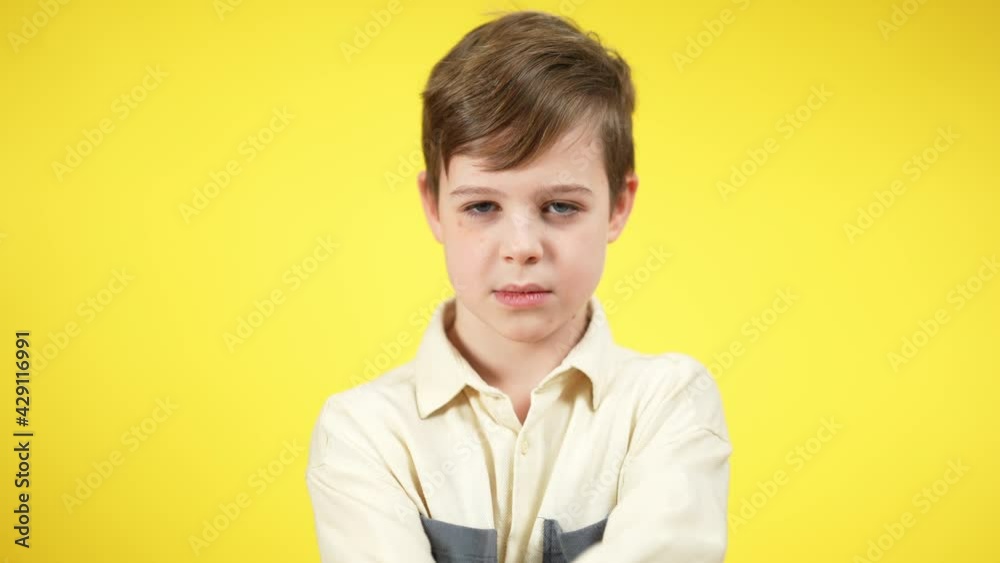 Unhappy Caucasian boy crossing hands shaking head no looking at camera. Portrait of dissatisfied sad kid posing at yellow background. Rejection and disapproval concept Unhappy Caucasian boy crossing hands shaking head no looking at camera. Portrait of dissatisfied sad kid posing at yellow background. Rejection and disapproval concept