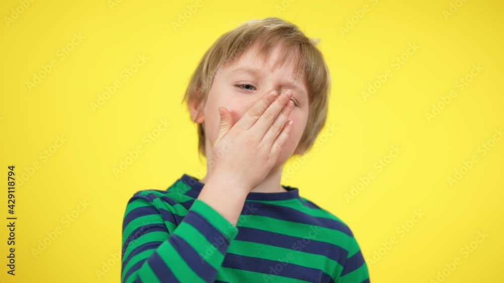 Close-up portrait of tired little boy yawning at yellow background. Exhausted Caucasian blond child with sad facial expression. Tiredness and exhaustion concept Close-up portrait of tired little boy yawning at yellow background. Exhausted Caucasian blond child with sad facial expression. Tiredness and exhaustion concept