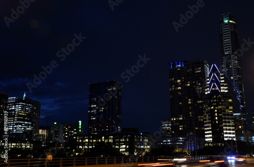 Night skyline over bridge with passing cars and lighted buildings